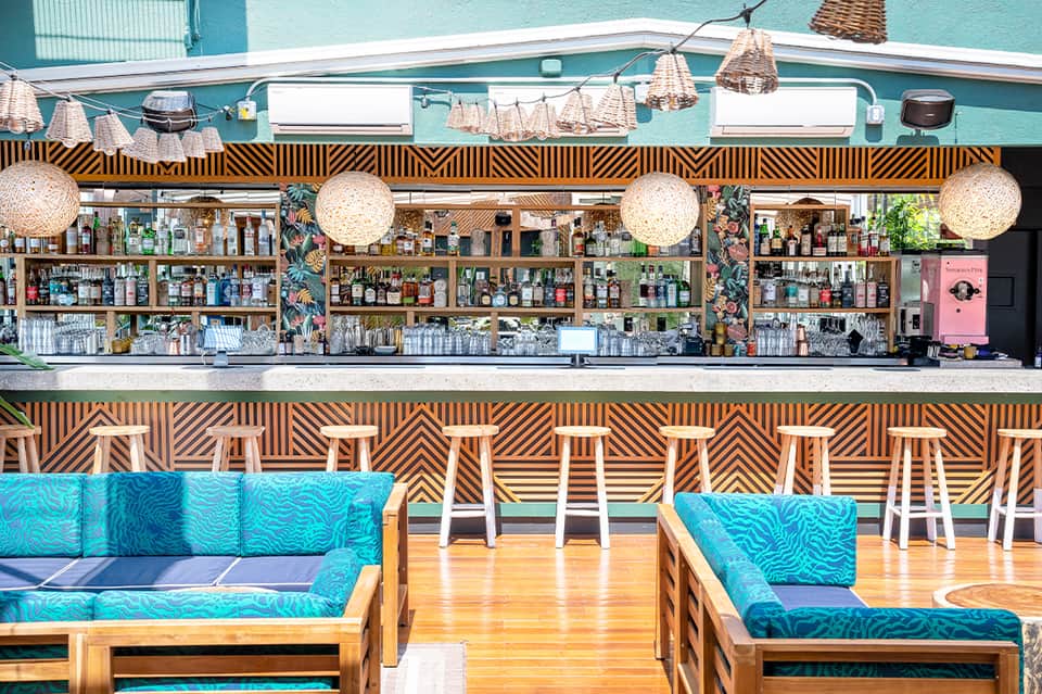 Modern bar with geometric patterned backdrop, woven pendant lights, and turquoise accents