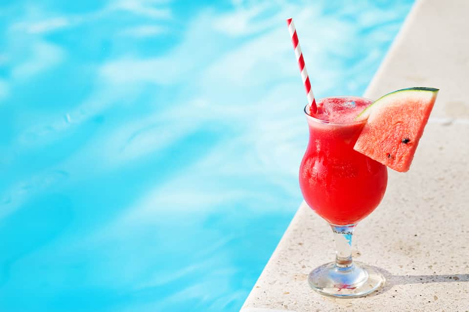 Red tropical cocktail with watermelon slice at poolside