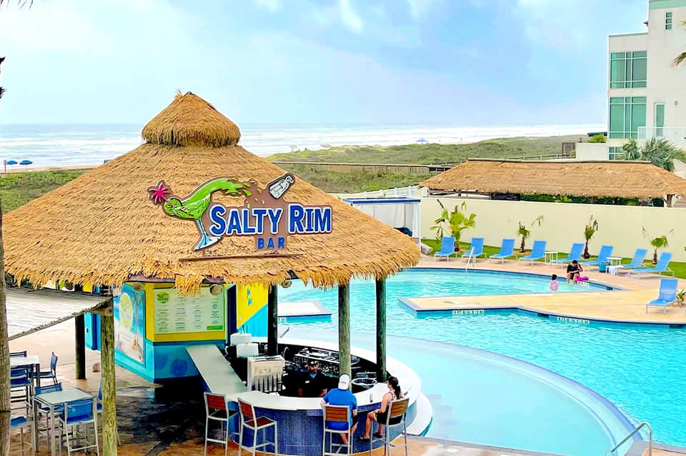 Salty Rim Bar tiki hut poolside with beach access and bright blue lounge chairs