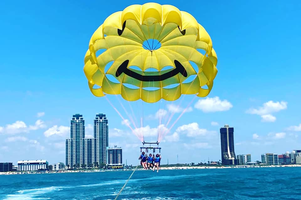 Parasailing adventure with yellow parachute over turquoise ocean near beachfront hotels