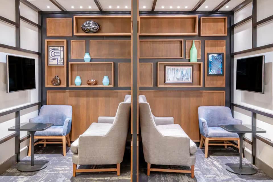 Luxury spa relaxation room with symmetrical wooden shelving, chairs, and accent lighting