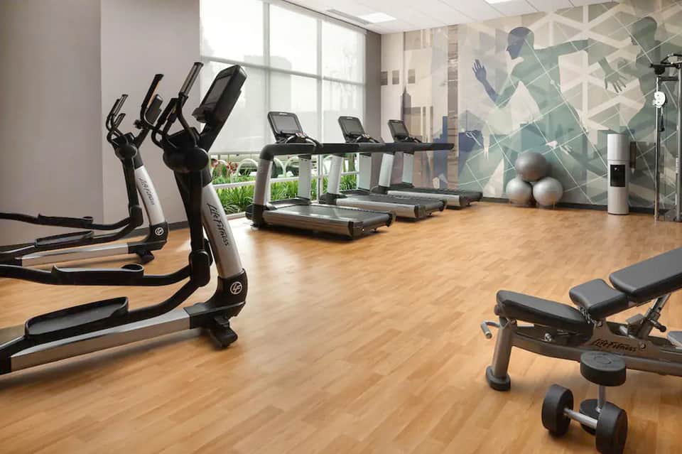 Bright fitness center with exercise bikes, treadmills, and large windows