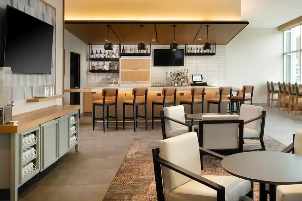 Contemporary resort bar and lounge with wood counter, leather seating, and full bar setup