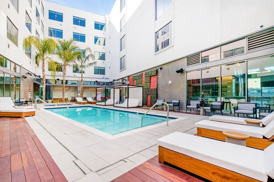 Resort courtyard with rectangular turquoise pool, lounge chairs, and surrounding white buildings