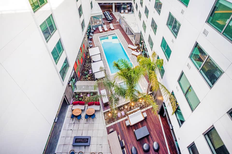 Overhead view of a narrow courtyard pool surrounded by white residential buildings with lounge chairs