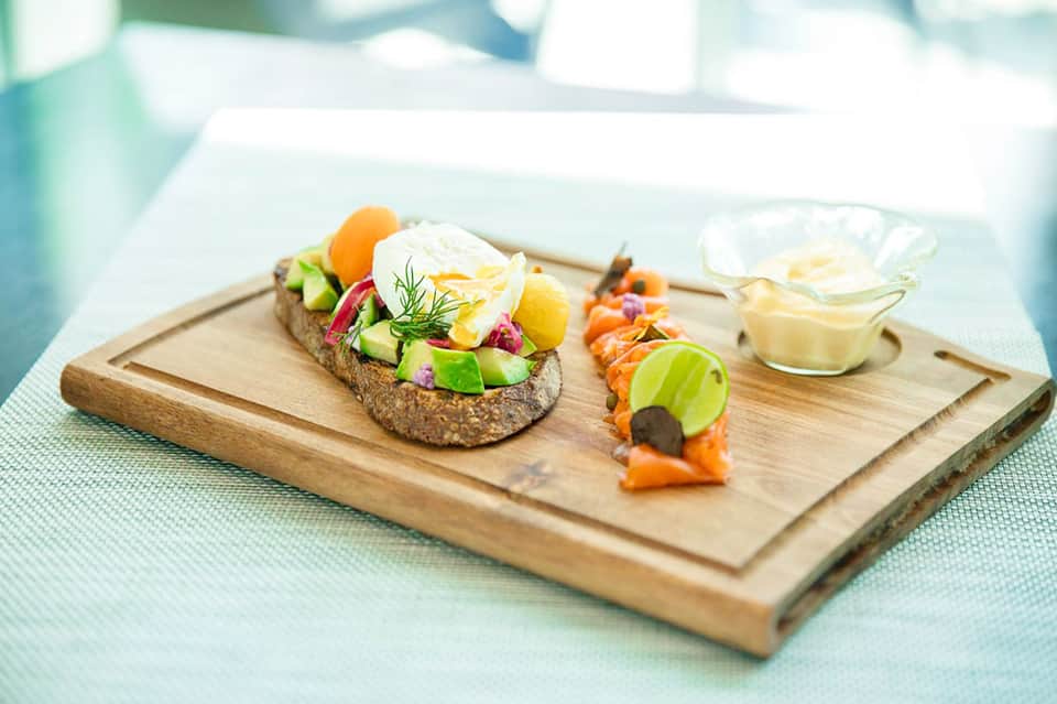 Elegant plated appetizers on wooden board featuring poached egg, vegetables, and salmon