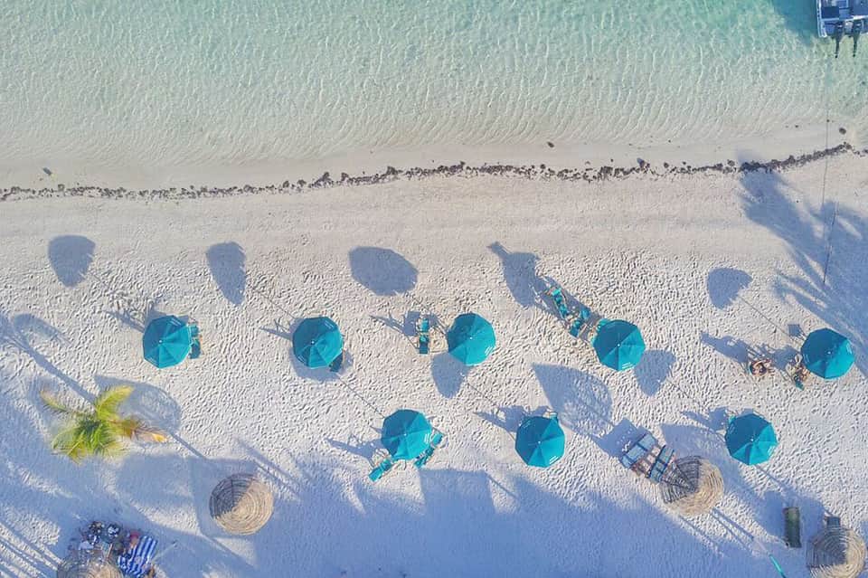 Aerial view of pristine white sand beach with turquoise umbrellas and loungers