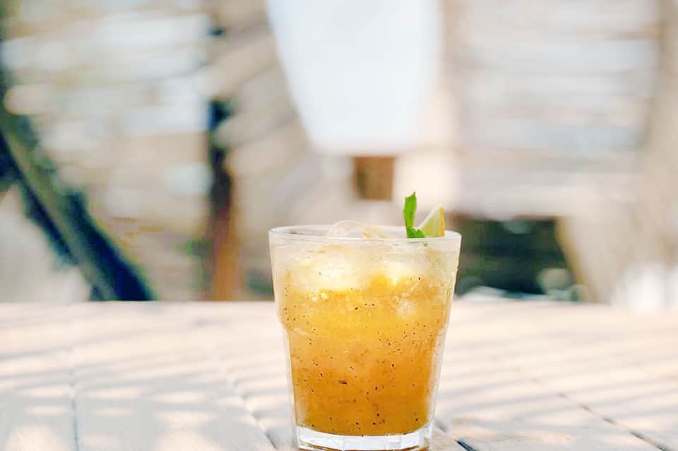 Tropical beverage with lime garnish on white wooden table with blurred background