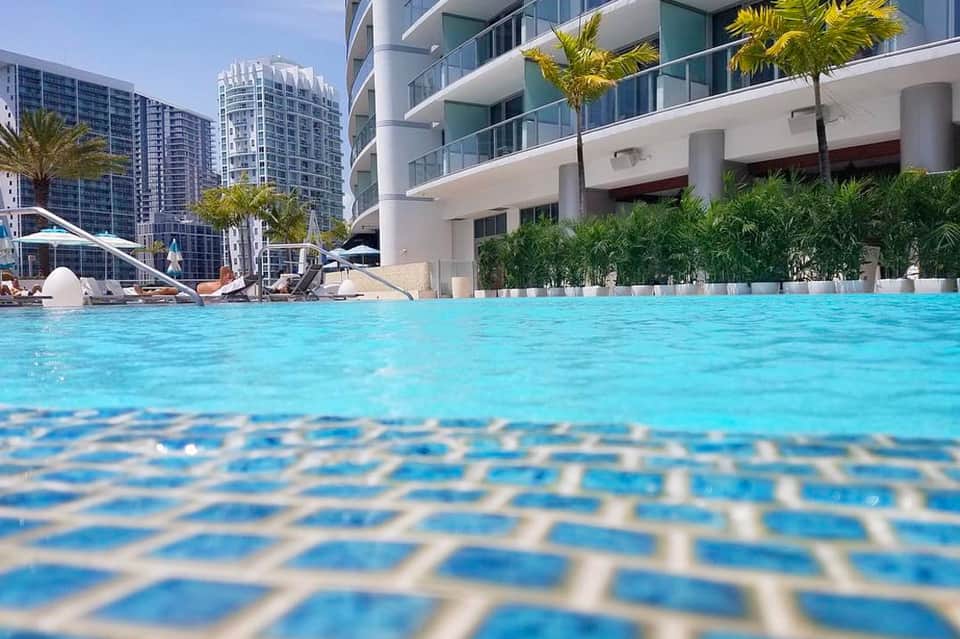 Resort pool with crystal-clear turquoise water and modern high-rise buildings in background