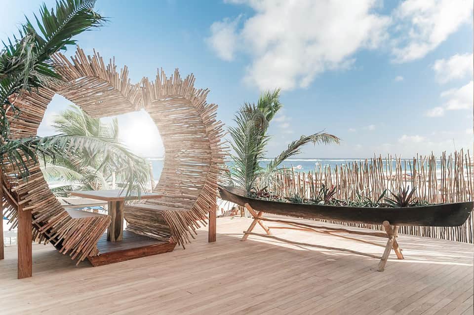 Wooden deck with sculptural palm frond installations and ocean views at a beach resort