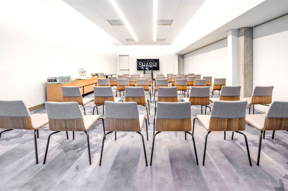Modern conference room with wooden chairs and glass refreshment station