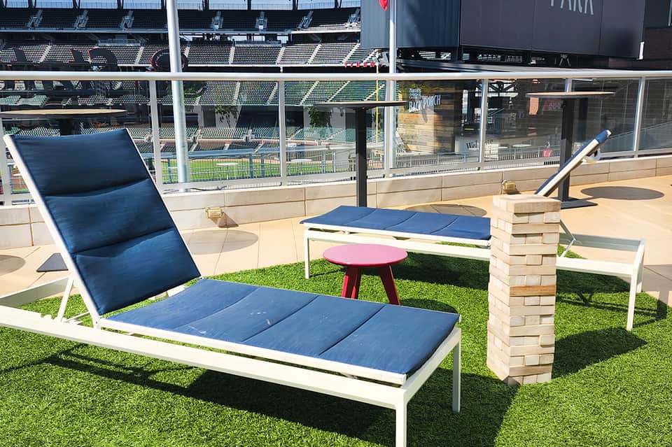 Lounge seating area overlooking stadium with blue cushioned chairs and artificial turf on elevated deck