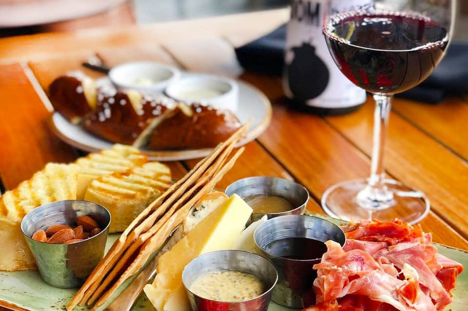Asian cuisine spread with wine glass, chopsticks, and dipping sauces on wooden table
