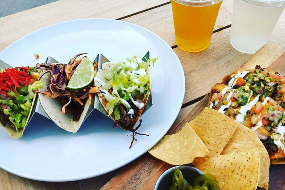 Beachside dining plate with tacos, fresh seafood, and tropical beverages on wooden table