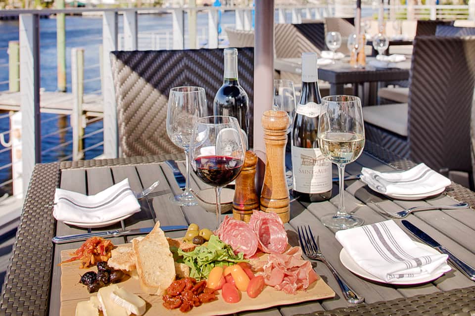 Waterfront dining table set with wine, appetizers, glasses, and ocean view in background