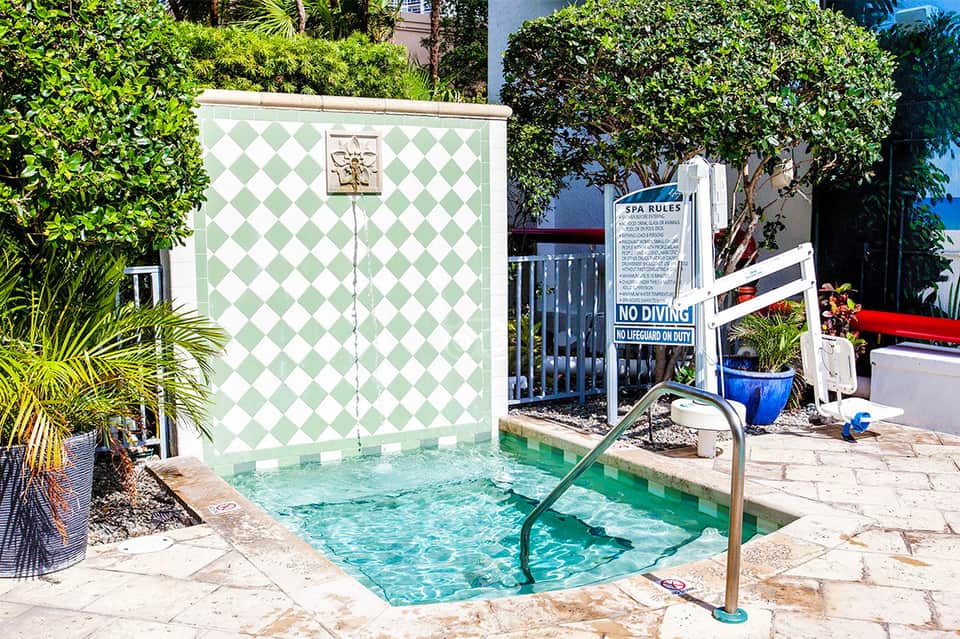 Small decorative pool with green and white diamond pattern walls and spa rules sign