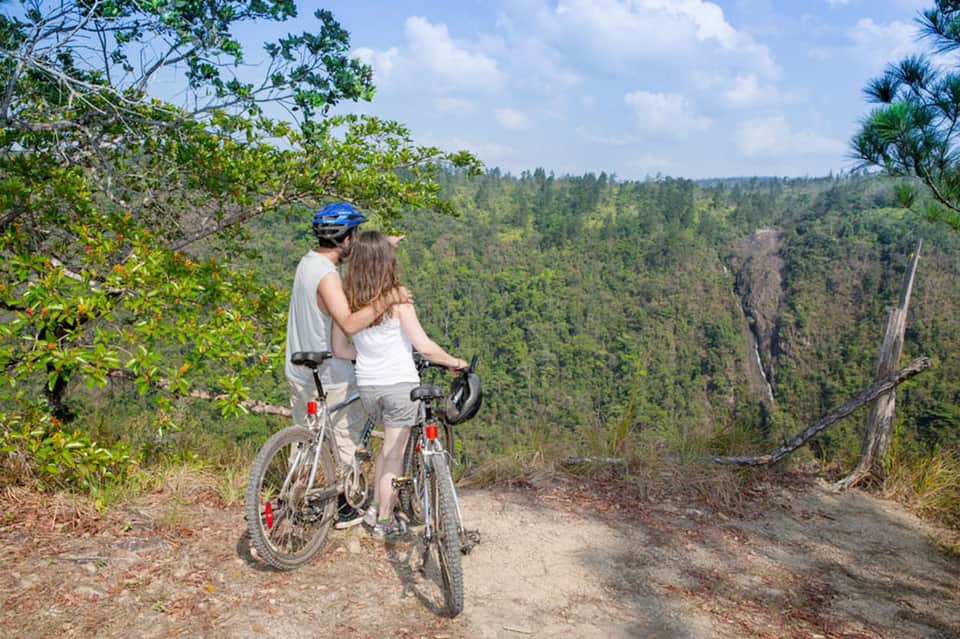 Couple on bicycle overlooking vast forested landscape and mountain valley