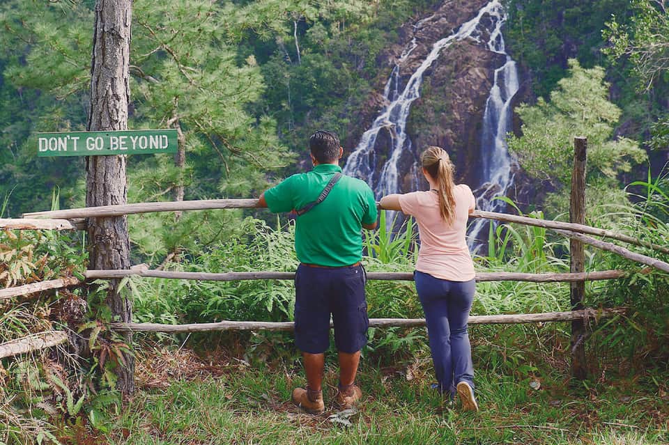 Couple viewing waterfall from wooden observation deck in lush forest setting