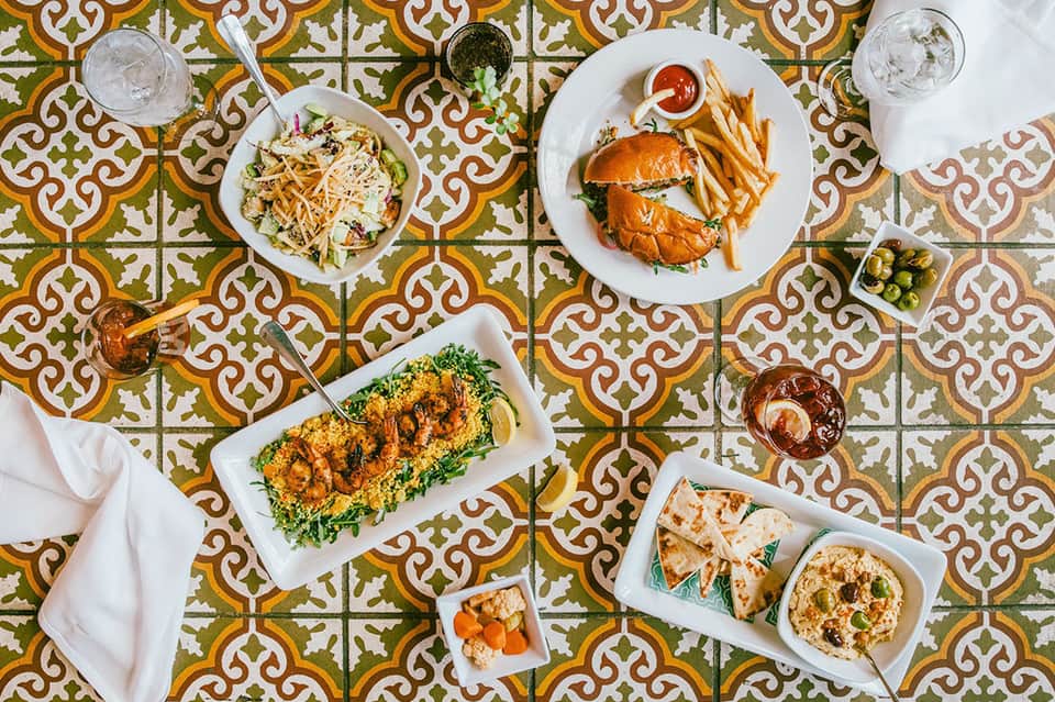 Overhead view of restaurant table with Mediterranean dishes, colorful patterned tile floor