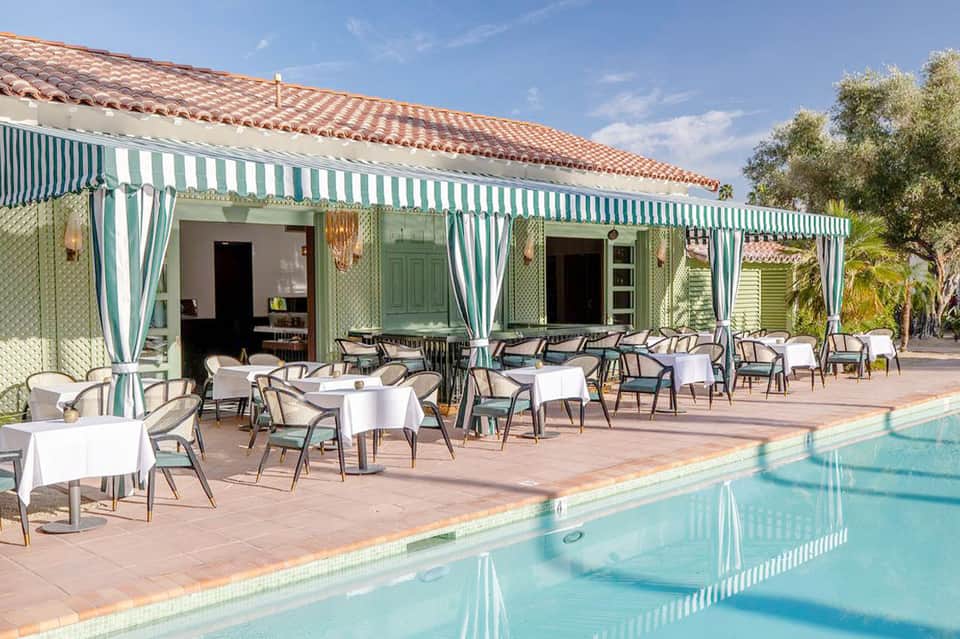 Charming poolside restaurant with green and white striped awning and turquoise pool