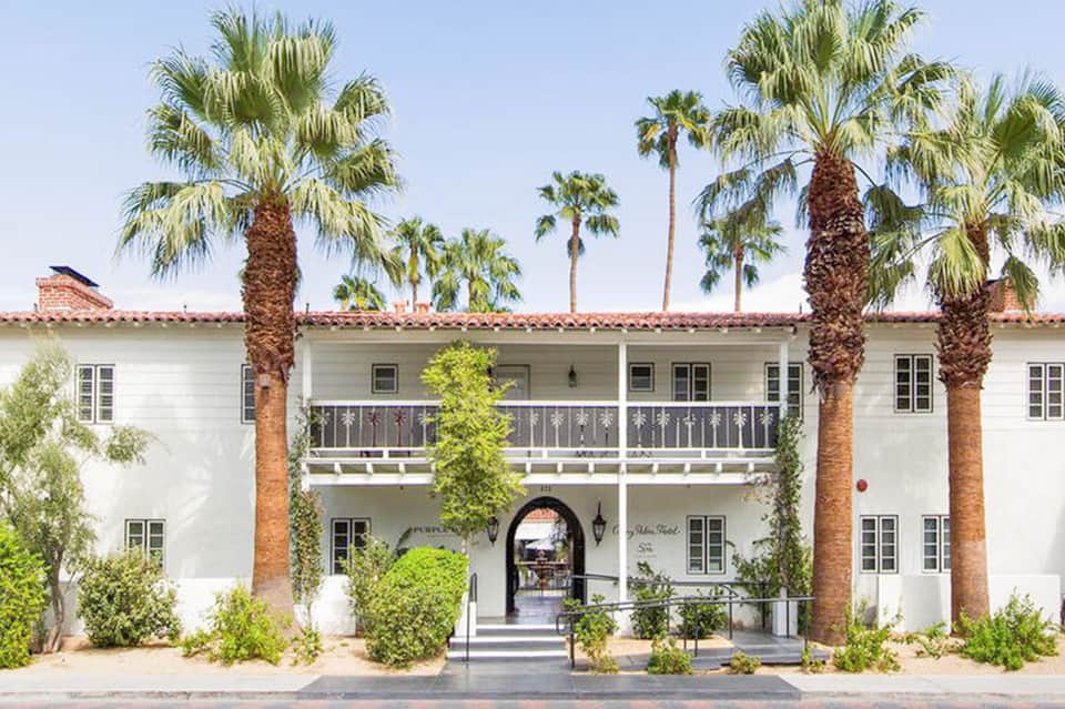 Spanish colonial-style white building with palm trees and wrought iron balcony railings