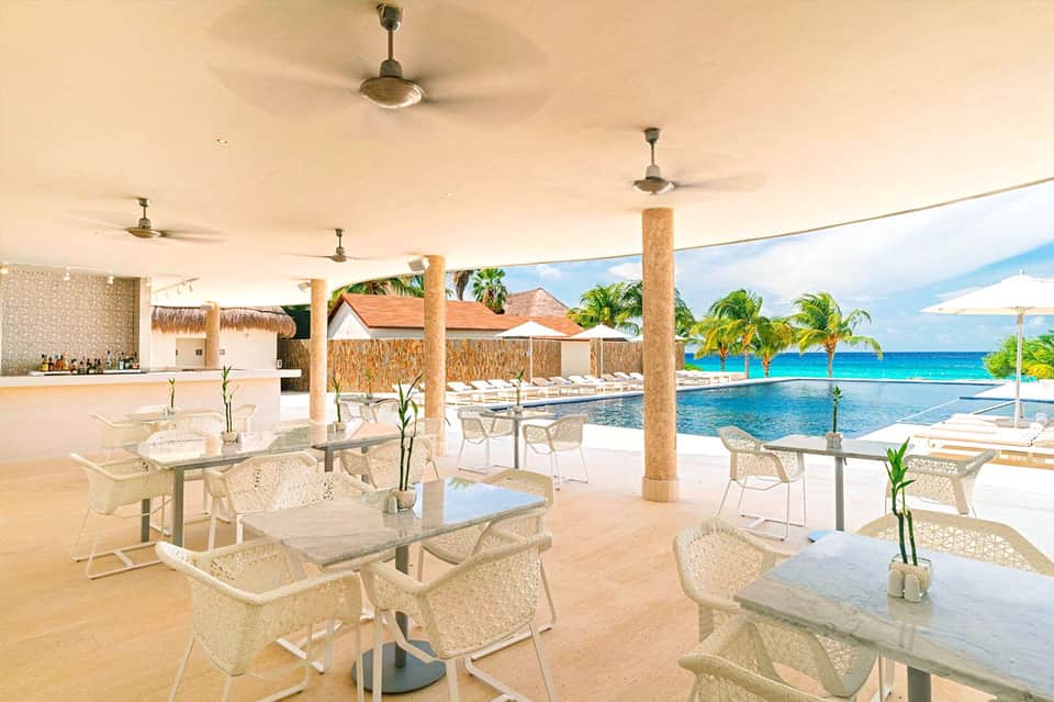 Beachfront restaurant pavilion with ocean views, lounge seating, and thatched roof details