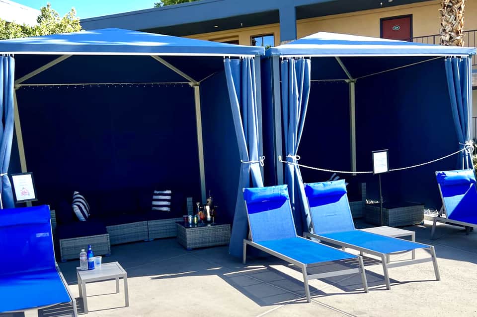 Modern blue cabana loungers with curtains and shade on resort patio