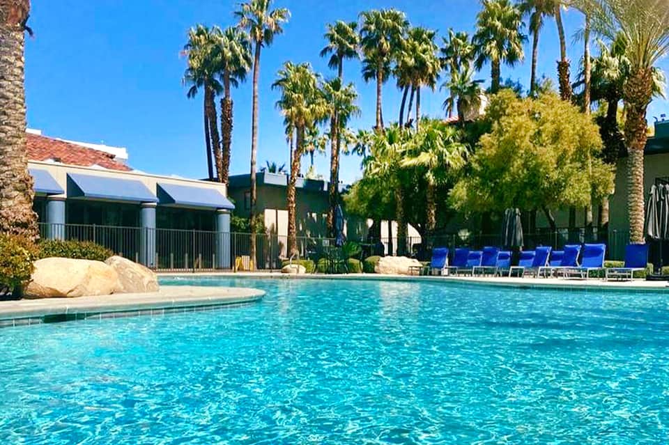 Large swimming pool surrounded by palm trees and resort buildings