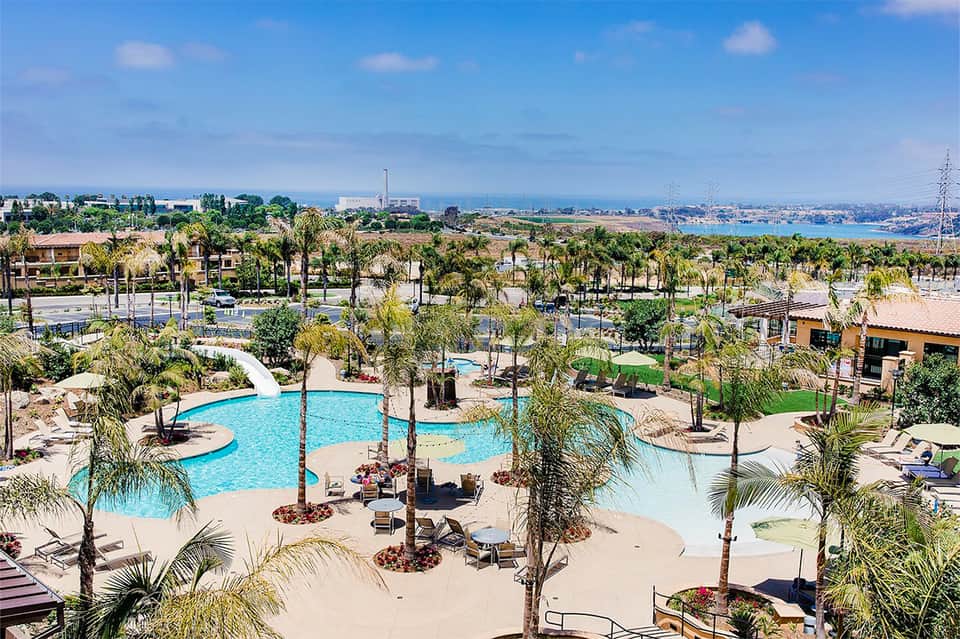 Expansive resort pool complex with lazy river, palm trees, and bay view in background