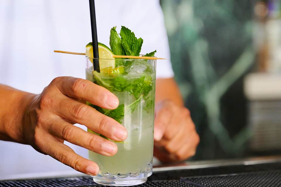 Mojito cocktail with mint and lime garnish held at bar