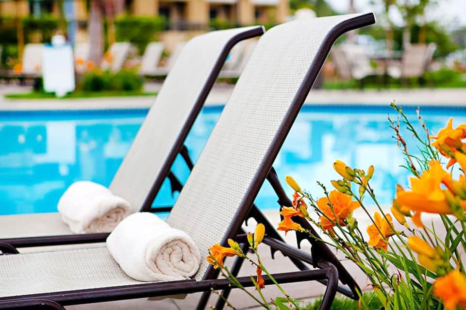 Pair of white cushioned lounge chairs beside a bright blue swimming pool