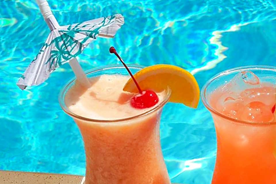 Tropical cocktails with umbrellas and fruit garnishes poolside