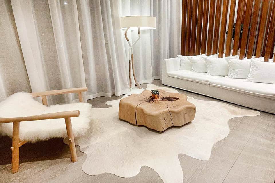 Minimalist modern living room with white sofa, wooden furniture, light wood floors, and floor-to-lamp lighting