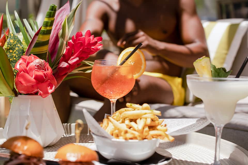 Tropical poolside cocktails and appetizers with colorful flowers and blurred guests