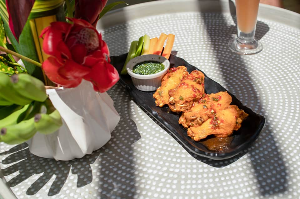 Appetizer plate with fried items, green sauce, and fresh flowers on dining table