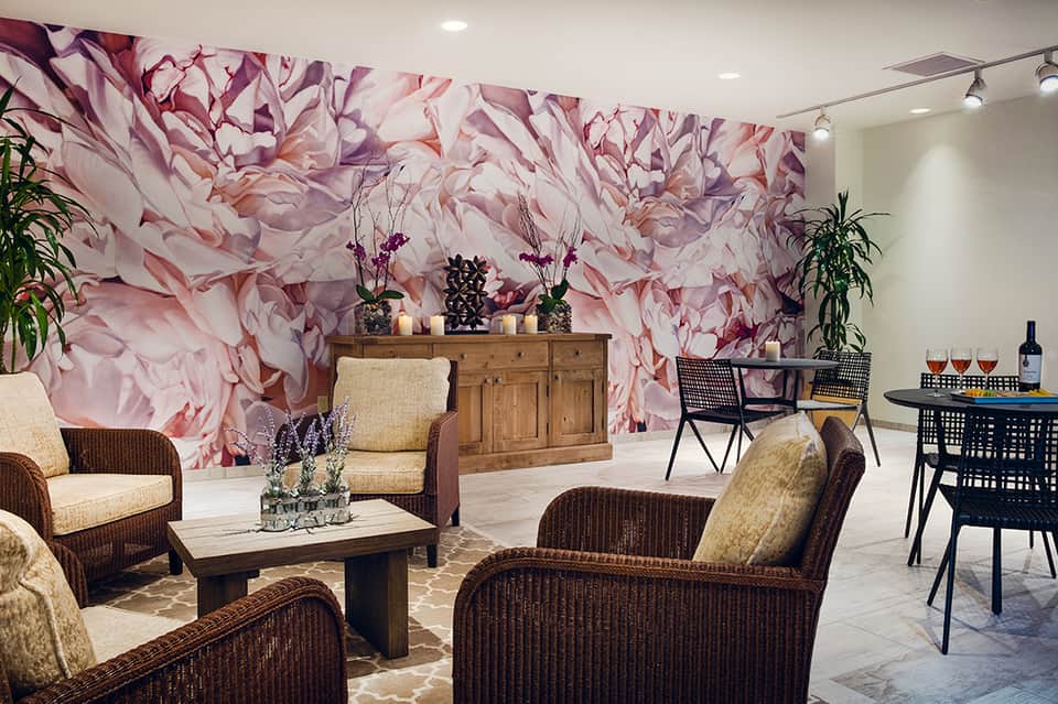 Elegant hotel lounge with pink floral wallpaper, rattan seating, and ambient lighting