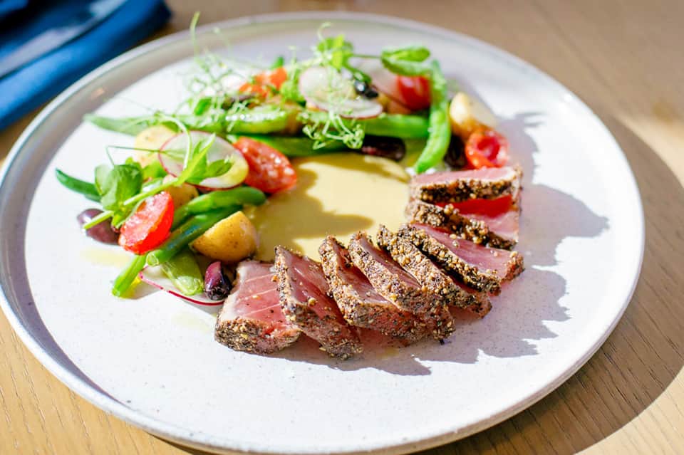 Artfully plated gourmet meal with seared meat, vegetables, and sauce on white plate