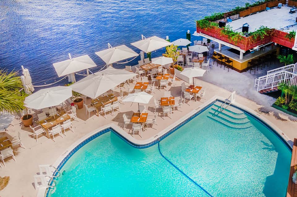 Waterfront pool deck with lounge chairs, umbrellas, and calm water views at upscale resort