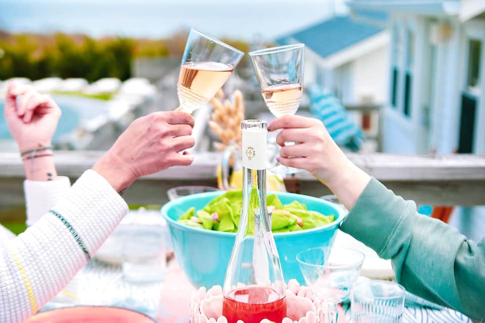 Two people toasting with wine glasses at outdoor poolside dining area