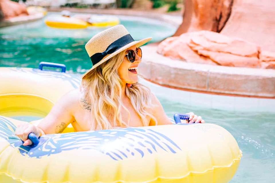 Woman in straw hat and sunglasses relaxing in yellow pool float at resort