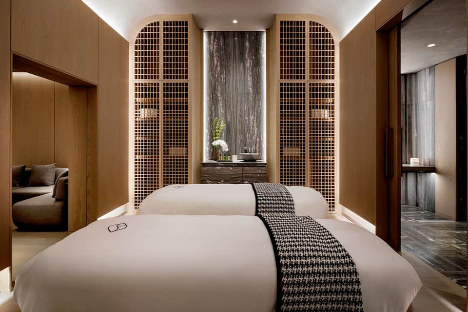 Luxury spa treatment room with two massage beds and wooden accents