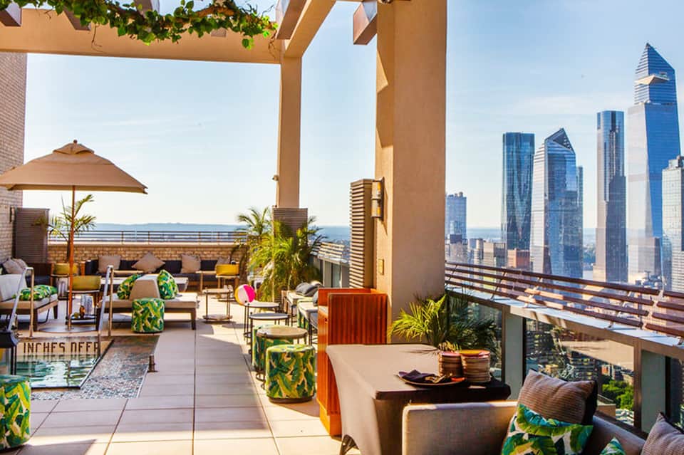 Luxury rooftop terrace with modern furniture, ocean views, and city skyline in background