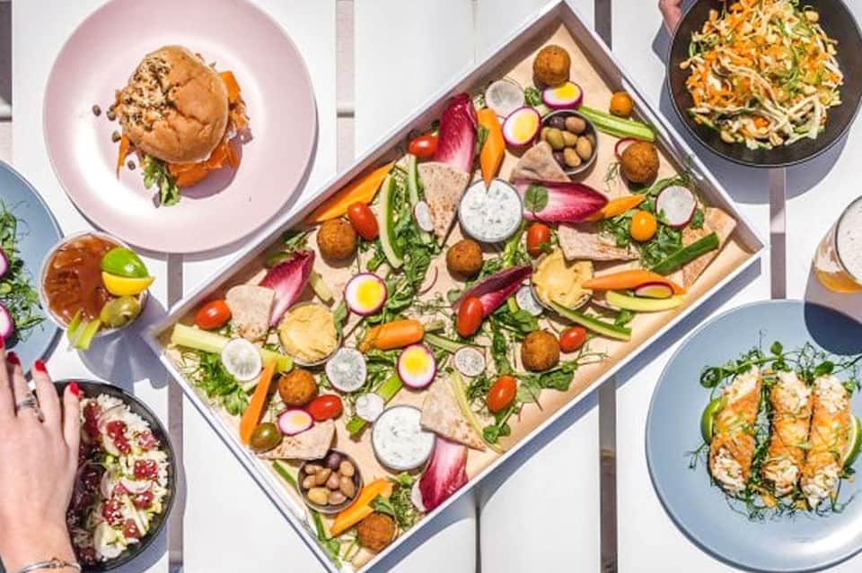 Overhead view of gourmet dishes and fresh ingredient board on white surface