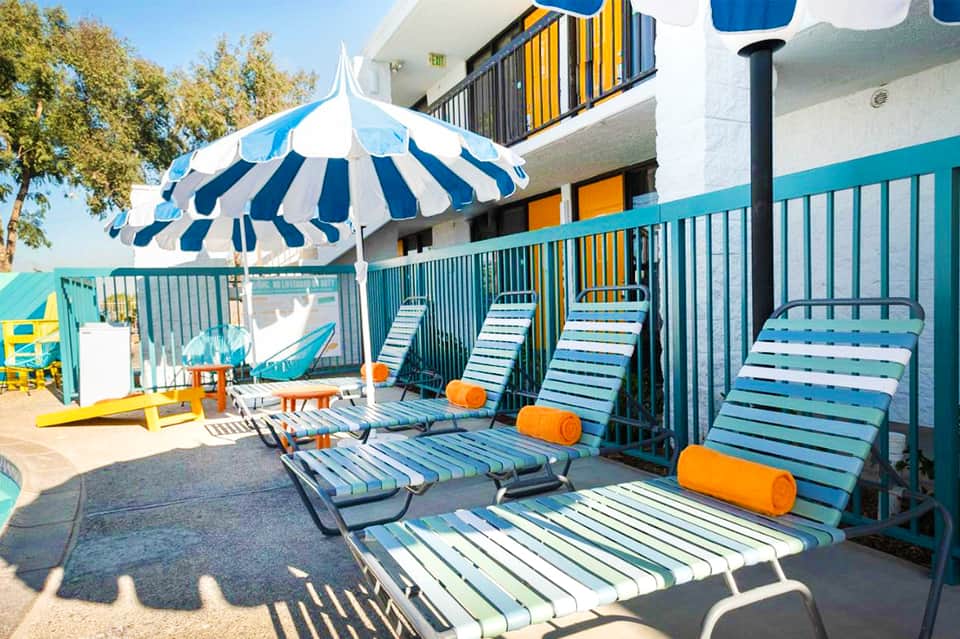 Colorful kids' beach area with blue and white striped lounge chairs, umbrellas, and playground