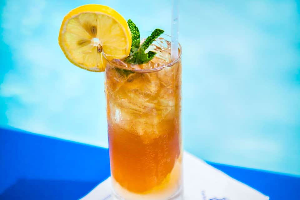 Tropical cocktail with lemon slice and mint garnish on blue background