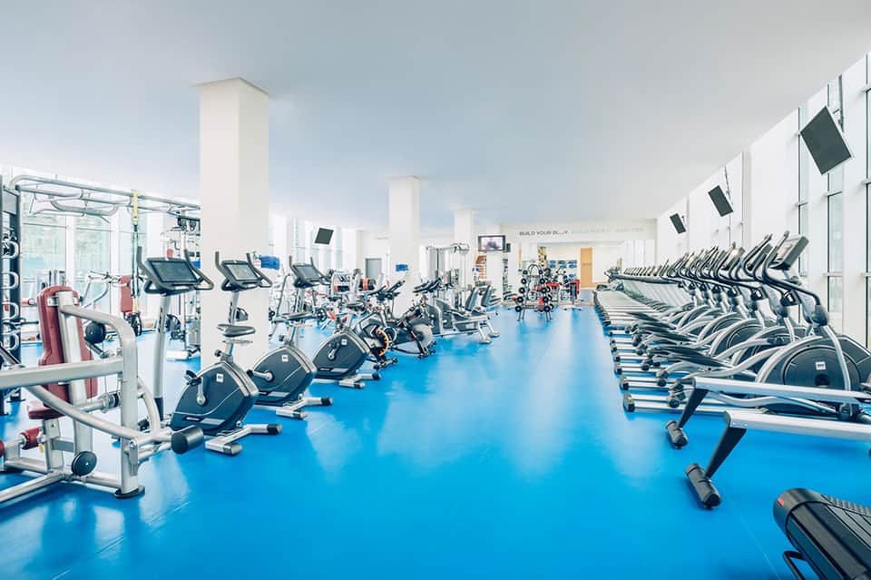 State-of-the-art fitness center with rows of exercise bikes and cardio equipment on blue flooring