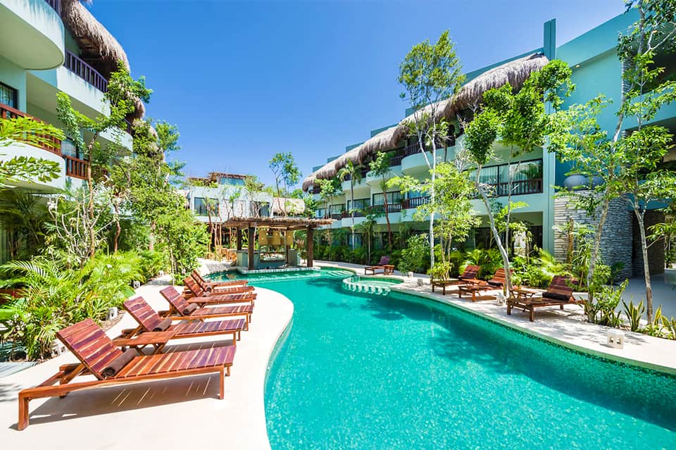 Tropical resort courtyard pool surrounded by lush greenery and multi-story lodging buildings