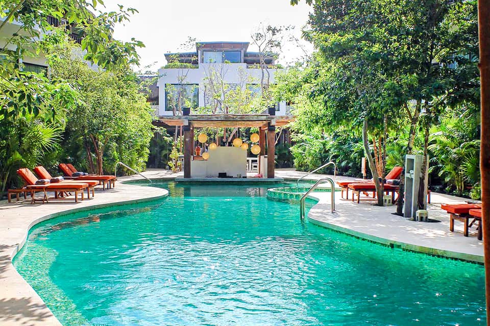 Tropical resort pool surrounded by lush greenery and wooden pergola