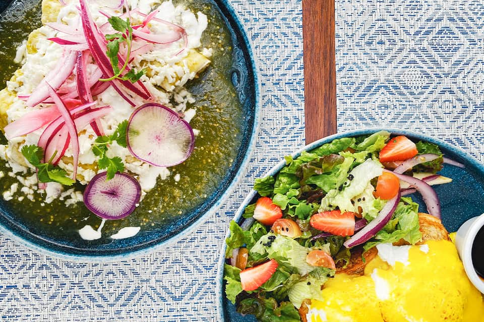 Two blue bowls with ceviche and fresh salad with radishes on textured placemat