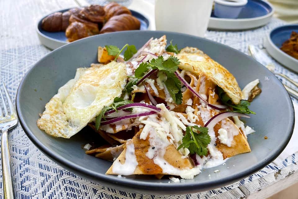 Plated breakfast dish with omelet, crispy potatoes, and fresh herbs